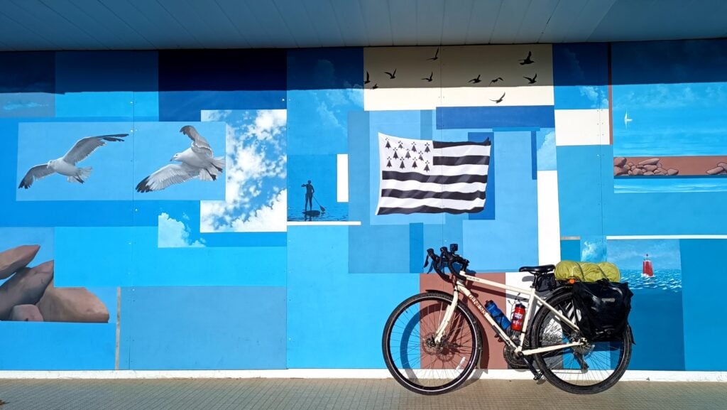 touring bike leaning against a wall with the brittany flag